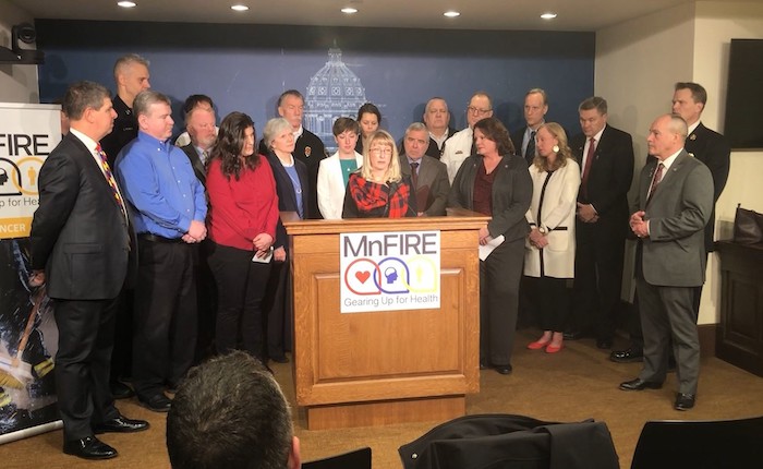 People gathered by podium at MN Firefighter health event