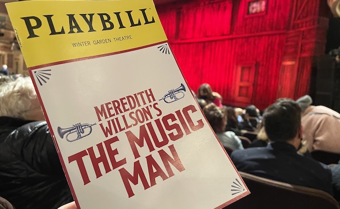 A Playbill for The Music Man is held up in front of a stage