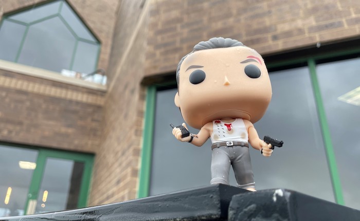 An action figure of Bruce Willis in Die Hard is set on the edge of a buildling