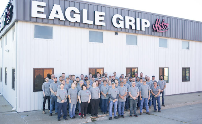 A group of employees stand in front of a new warehouse buidling