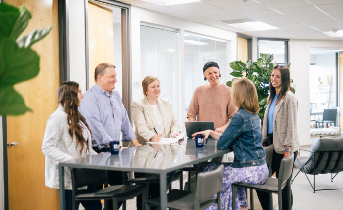 Six Bellmont Partners team members collaborate around a high-top table