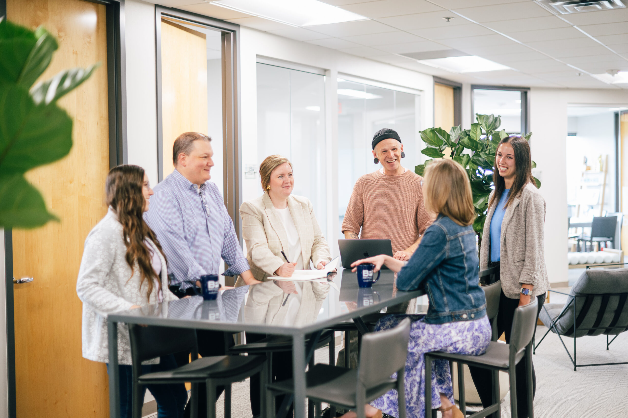 Six Bellmont Partners team members collaborate around a high-top table