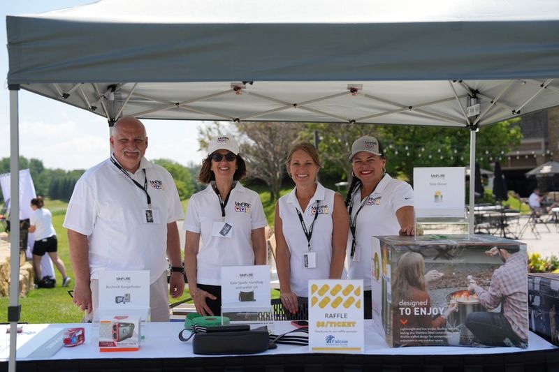 Volunteers gather behind a prize table at a fundraising event.